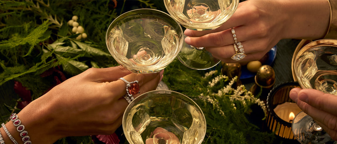 Close-up of a group toasting while wearing gemstone and diamond jewelry.